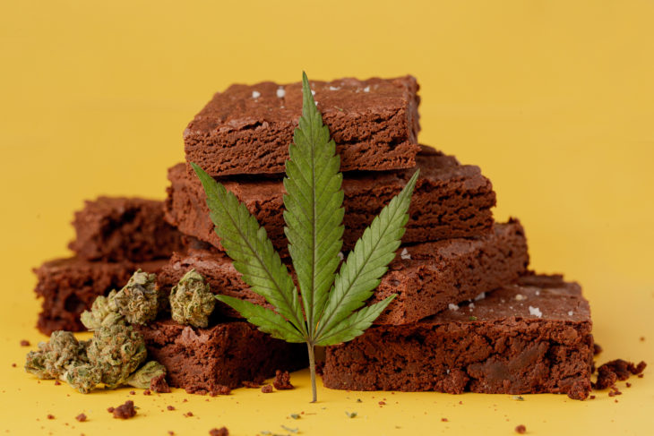 Marijuana leaf in front of nicely displayed stacks of delicious chocolate fudge brownies